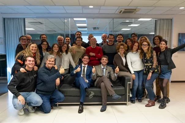 Foto di gruppo dei partecipanti a un corso per dentisti, riuniti attorno a un divano in sala corsi